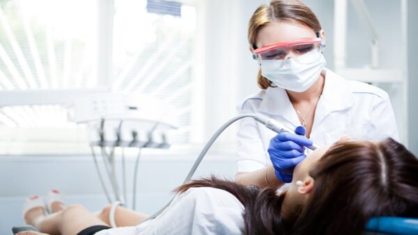 A dentist is using an electric toothbrush to clean the teeth of a patient.